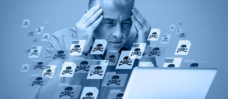 Man holding his head in front of a laptop